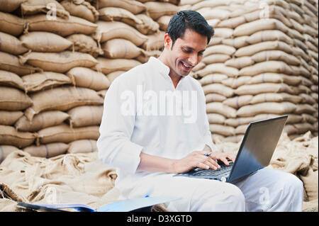 L'homme à l'aide d'un ordinateur portable dans un marché des céréales, l'Anaj, Mandi, Sohna Gurgaon, Haryana, Inde Banque D'Images