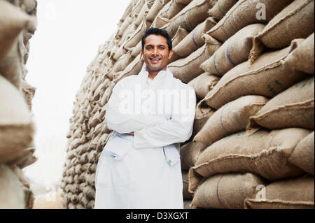 Homme debout près de piles de sacs de blé dans un entrepôt, Anaj, Mandi, Sohna Gurgaon, Haryana, Inde Banque D'Images