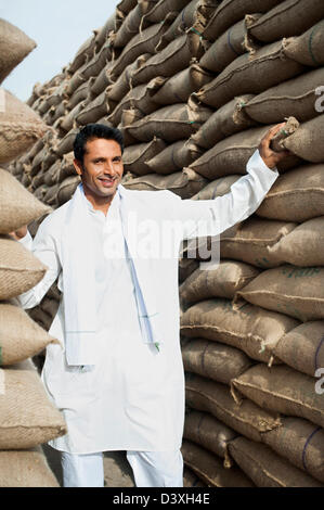 Homme debout près de piles de sacs de blé dans un entrepôt, Anaj, Mandi, Sohna Gurgaon, Haryana, Inde Banque D'Images