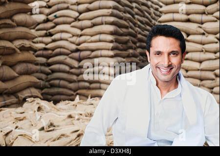 Man smiling près de sacs de grains de blé, Anaj, Mandi, Sohna Gurgaon, Haryana, Inde Banque D'Images