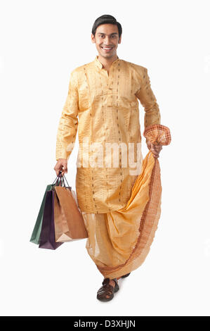 Bengali man carrying shopping bags and smiling Banque D'Images