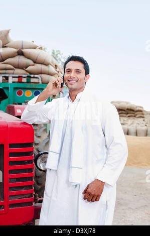 Homme debout près d'un tracteur à parler sur un téléphone mobile, l'Anaj, Mandi, Sohna Gurgaon, Haryana, Inde Banque D'Images