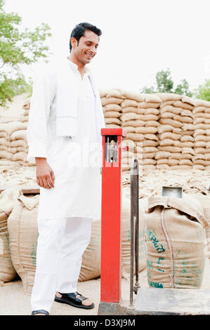 Homme sac de blé pesant sur une échelle, l'Anaj, Mandi, Sohna Gurgaon, Haryana, Inde Banque D'Images