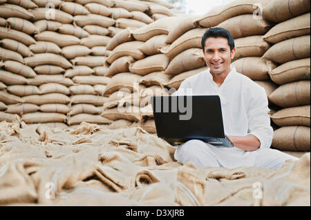 L'homme à l'aide d'un ordinateur portable dans un marché des céréales, l'Anaj, Mandi, Sohna Gurgaon, Haryana, Inde Banque D'Images