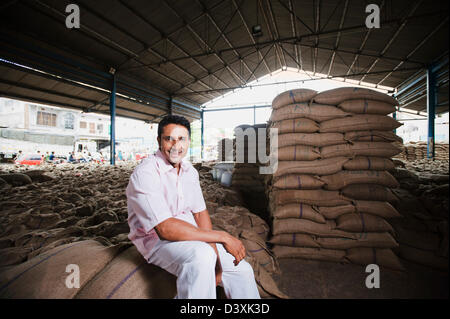 Homme assis sur pile de sacs de blé dans un entrepôt, Anaj, Mandi, Sohna Gurgaon, Haryana, Inde Banque D'Images