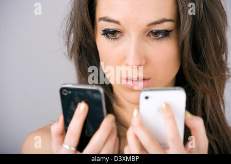 Jeune femme à l'aide de deux iPhones. Banque D'Images