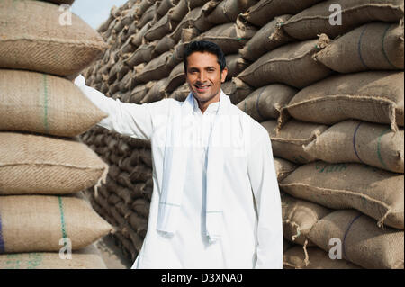 Homme debout près de piles de sacs de blé dans un entrepôt, Anaj, Mandi, Sohna Gurgaon, Haryana, Inde Banque D'Images