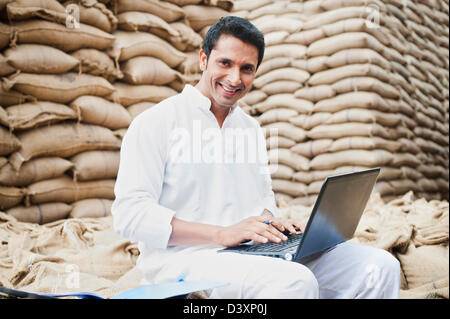 L'homme à l'aide d'un ordinateur portable dans un marché des céréales, l'Anaj, Mandi, Sohna Gurgaon, Haryana, Inde Banque D'Images