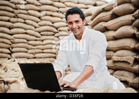 L'homme à l'aide d'un ordinateur portable dans un marché des céréales, l'Anaj, Mandi, Sohna Gurgaon, Haryana, Inde Banque D'Images