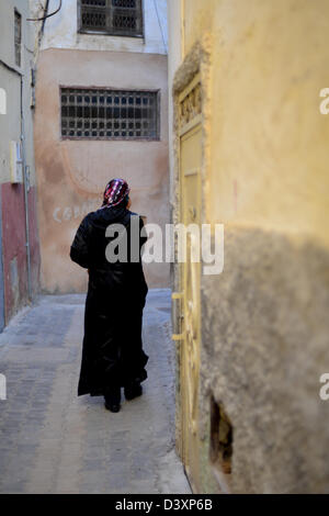 Retour d'une djellaba marocaine femme portant un foulard et marche loin de Médine Banque D'Images