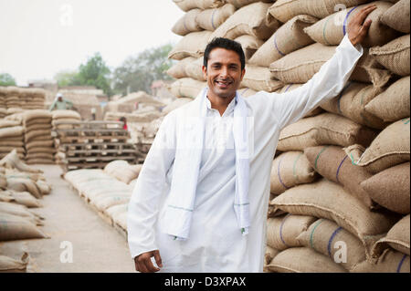 Homme debout près de piles de sacs de blé dans un entrepôt, Anaj, Mandi, Sohna Gurgaon, Haryana, Inde Banque D'Images