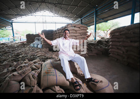 Homme assis sur pile de sacs de blé dans un entrepôt, Anaj, Mandi, Sohna Gurgaon, Haryana, Inde Banque D'Images