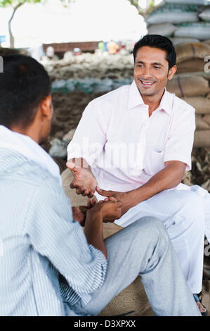 Man showing échantillon de blé à un client, Anaj, Mandi, Sohna Gurgaon, Haryana, Inde Banque D'Images