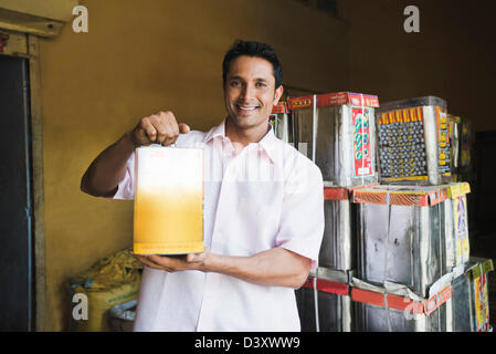 Homme montrant une cartouche d'huile alimentaire dans un magasin, Sohna, Gurgaon, Haryana, Inde Banque D'Images