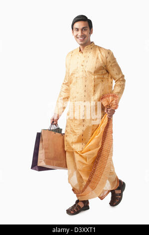Bengali man carrying shopping bags and smiling Banque D'Images