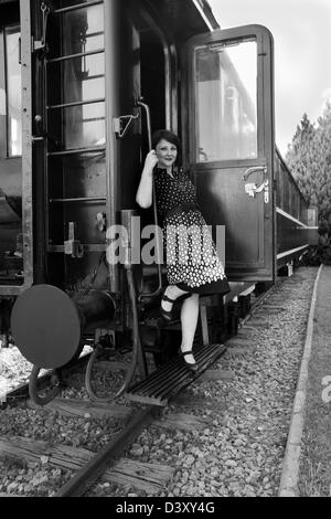 Une belle jeune femme au style des années 1950 stepping off train Banque D'Images