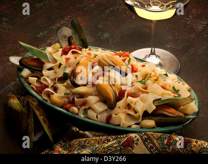 Un plat de pâtes aux moules tagliatelles,vert, l'ail, cannelini les haricots et le persil italien accompagné de vin blanc.. Banque D'Images