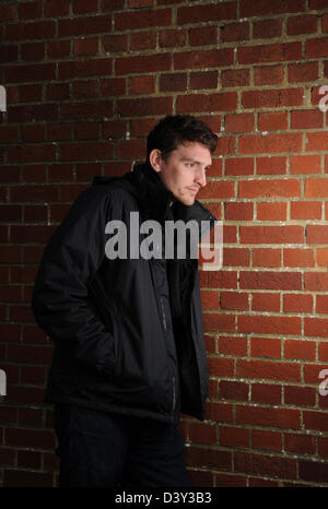 Photo de personnage générique homme contre mur de brique rouge posée par model wearing black North Face jacket Banque D'Images