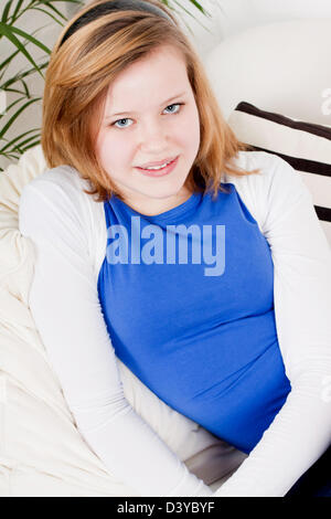 Happy teenager girl smiling sitting on couch et relaxant loisirs vie Banque D'Images