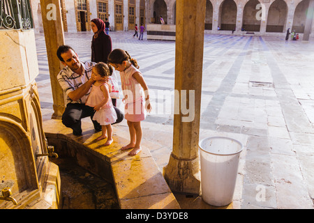 Père syrien de laver ses filles bébé à la fontaine des ablutions de la Grande Mosquée d'Alep. La Syrie Banque D'Images