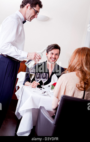 L'homme et la femme pour le dîner au restaurant waiter serving eau minérale Banque D'Images