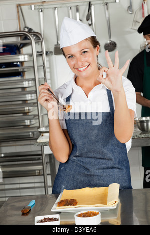 Femme Chef montrant Okay Sign In Kitchen Banque D'Images