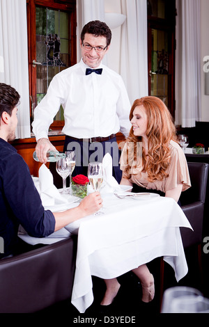 L'homme et la femme pour le dîner au restaurant waiter serving eau minérale Banque D'Images