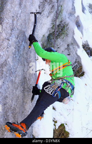 Alpiniste dans l'action avec deux axes sur une cascade de glace Banque D'Images