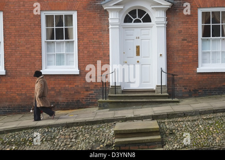 Femme en manteau de fourrure et chapeau marche dernières Georgian house no.38 dans Broad Street, Ludlow, Shropshire, Angleterre, Grande-Bretagne Banque D'Images