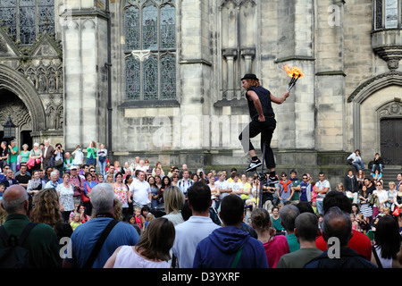 Damien Ryan, artiste de rue du Festival Fringe d'Édimbourg, redoutable et sérieux, qui accueille une foule qui se mêle du feu sur un cycle Uni, en Écosse, au Royaume-Uni, en Europe Banque D'Images