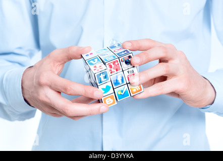 Businessman solving rubik's cube avec des logos de marque, médias sociaux. Banque D'Images