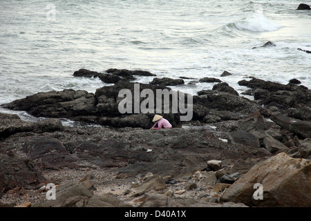 C'est une photo de la mer avec les rochers et les pierres. Nous pouvons voir un pêcheur au travail. Il y a des choses trop religieuse Banque D'Images