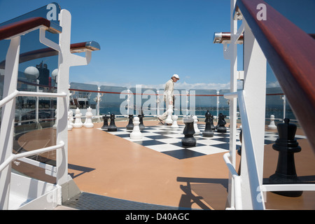 Passager sur bateau de croisière dispose les hommes d'échecs sur un immense échiquier. Banque D'Images