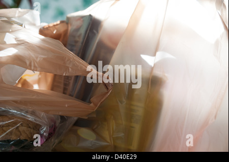 Les sacs d'épicerie en plastique éclairé par la lumière du soleil à travers une fenêtre de la cuisine. Banque D'Images