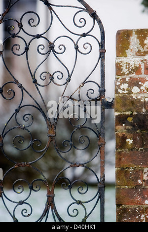 Partie d'ornements en fer forgé rouillé garden gate verrouillée sur mur couvert de lichens Banque D'Images