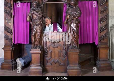 Pieds d'une personne dans une confession booth et le prêtre à l'écoute (tourné en une cité médiévale église du 17ème siècle) Banque D'Images