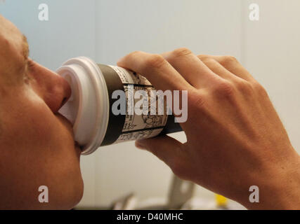 (Afp) une archive de fichiers photo, datée du 8 septembre 2011, montre un homme de boire du café dans une tasse de papier à Berlin, Allemagne. Photo : Alex Ehlers Banque D'Images