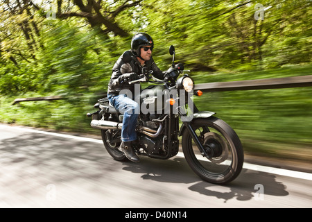 Homme en noir sur cuir moto Triumph scrambler, Londres Banque D'Images