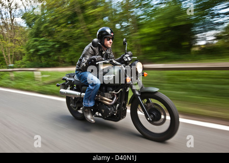 Homme en noir sur cuir moto Triumph scrambler, Londres Banque D'Images