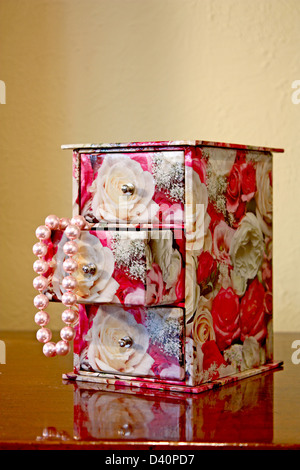 Perles roses dans une boîte de décoration sur une surface réfléchissante Banque D'Images
