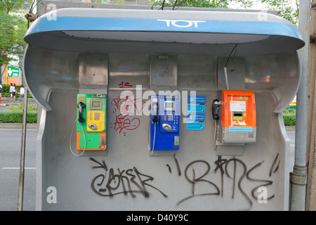 Trois téléphones publics dans un abri couvert de graffitis, Wireless Road, Bangkok Banque D'Images