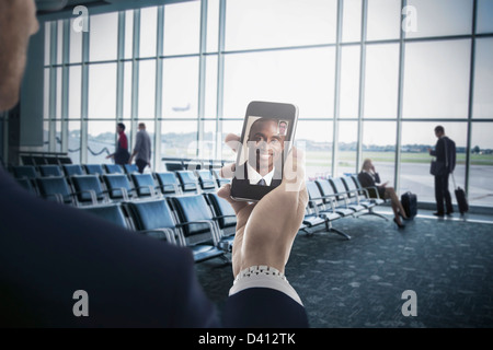 Businessman holding cell phone in airport Banque D'Images