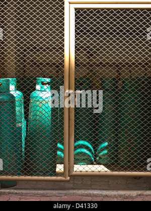 Les bouteilles de gaz dans une rangée derrière une clôture pour le fond Banque D'Images