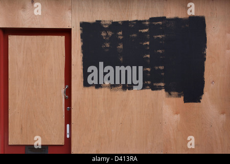 Une boutique anonyme porte et fenêtre a été condamné avec plyboard, identifier l'écriture masquée de peinture noire dans le centre de Londres, victime de la récession au Royaume-Uni. Banque D'Images