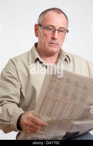 Homme mûr en 50s, la lecture d'un journal grand format. Banque D'Images