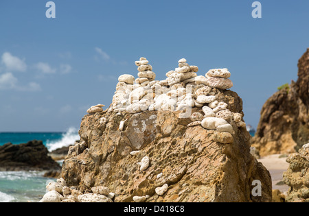 Plusieurs piles de cailloux sur la roche par la mer avec des pieux d'éclairage solaire Banque D'Images