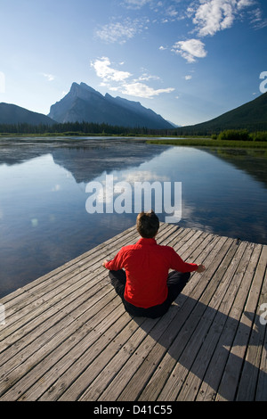 Homme de 54 ans méditant sur dock à Vermillion Lake, Banff, Alberta, Canada. Banque D'Images