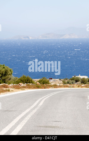 Naxos. Cyclades. La Grèce. Vue d'une route solitaire avec les eaux bleues de la mer Egée à l'arrière-plan. Banque D'Images