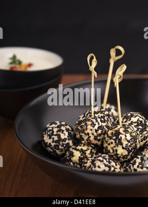 Boules de fromage de chèvre épicé roulé dans des graines de sésame. Banque D'Images