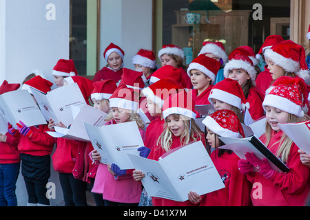 Un jeune chœur d'enfants habillés pour chanter Noël en ville l'auditoire. Banque D'Images